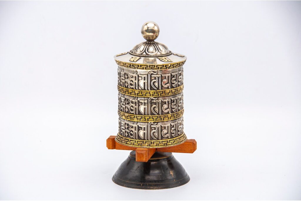 white metal tabletop prayer wheel features a triple-line Om Mani Padme Hum mantra. Handcrafted in Nepal and filled with sacred mantra scrolls.