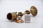 lose-up of engraved Om Mani Padme Hum mantra on Tibetan prayer wheel Bottom view of Vajra brass base on Buddhist prayer wheel Prayer wheel being held and spun – traditional dharma practice