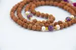 Rudraksha Mala with Pearl & Amethyst – handcrafted 108-bead prayer necklace combining sacred rudraksha seeds with calming pearl and spiritual amethyst, symbolizing protection, peace, and higher awareness. Ideal for meditation and spiritual growth.
